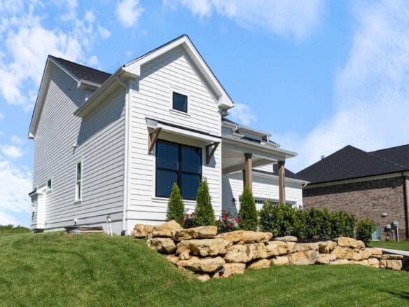 Modern white house with front porch, landscaped yard, and blue sky.