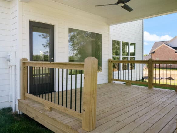 Newly built wooden deck with black metal railing in a residential backyard.