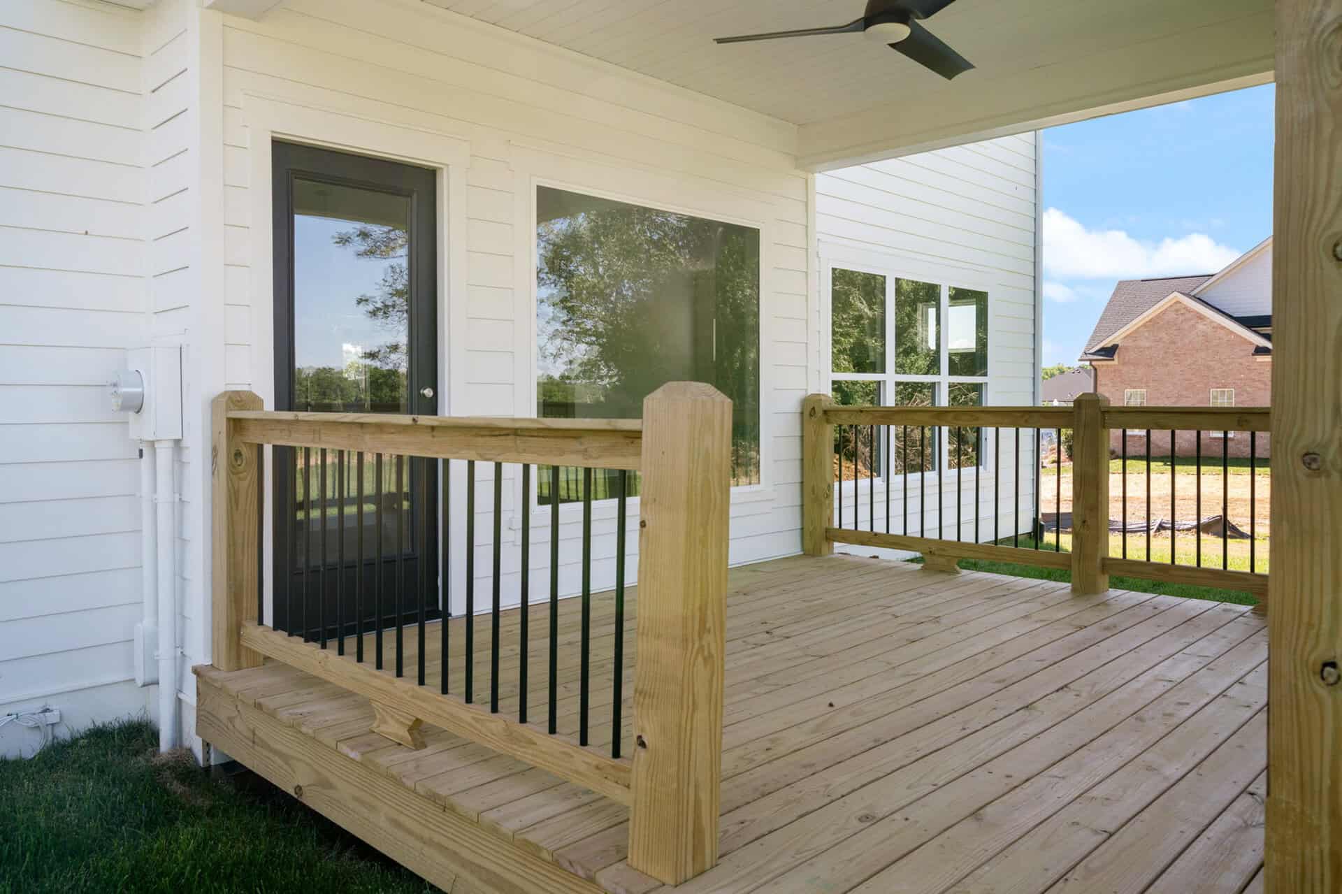 Newly built wooden deck with black metal railing in a residential backyard.