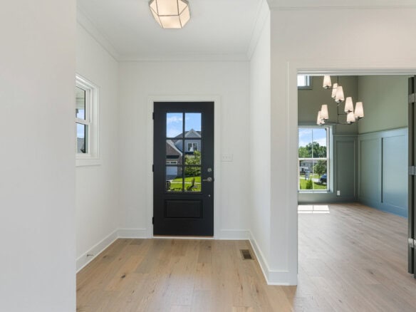 Bright entryway with black door and natural light from windows.