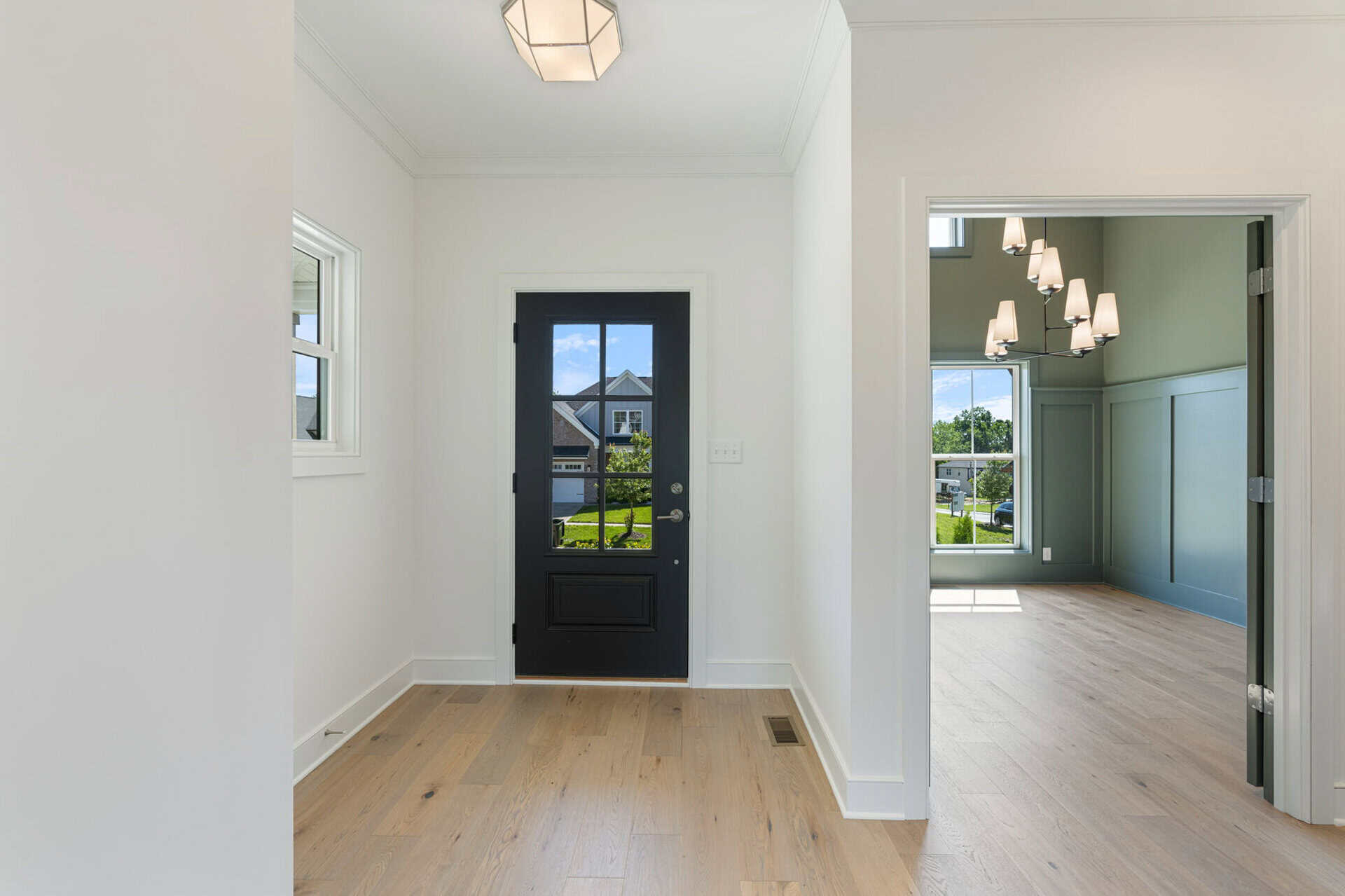 Bright entryway with black door and natural light from windows.