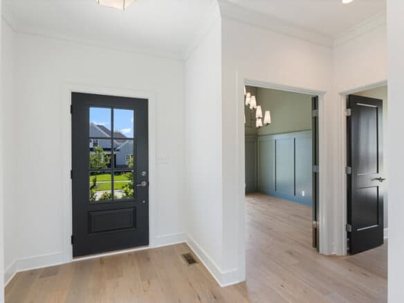 Modern interior entryway with black door and light wood flooring.