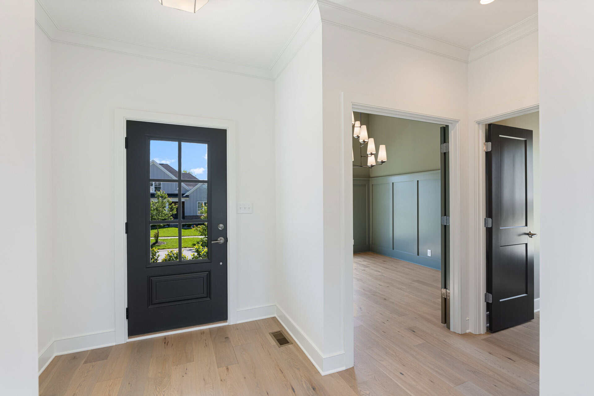 Modern interior entryway with black door and light wood flooring.