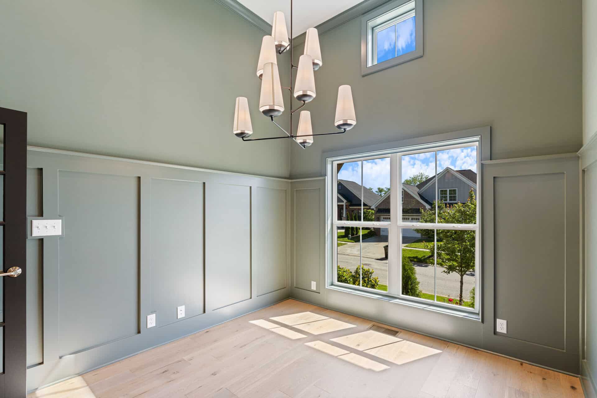 Bright living room with large window and modern chandelier in a new home.