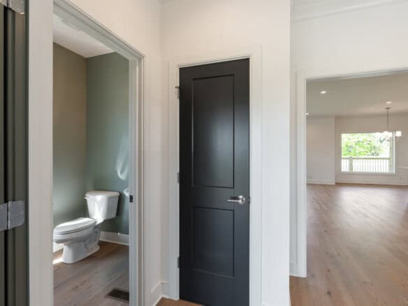 Interior view of a modern home with a bathroom, black door, and spacious living area.