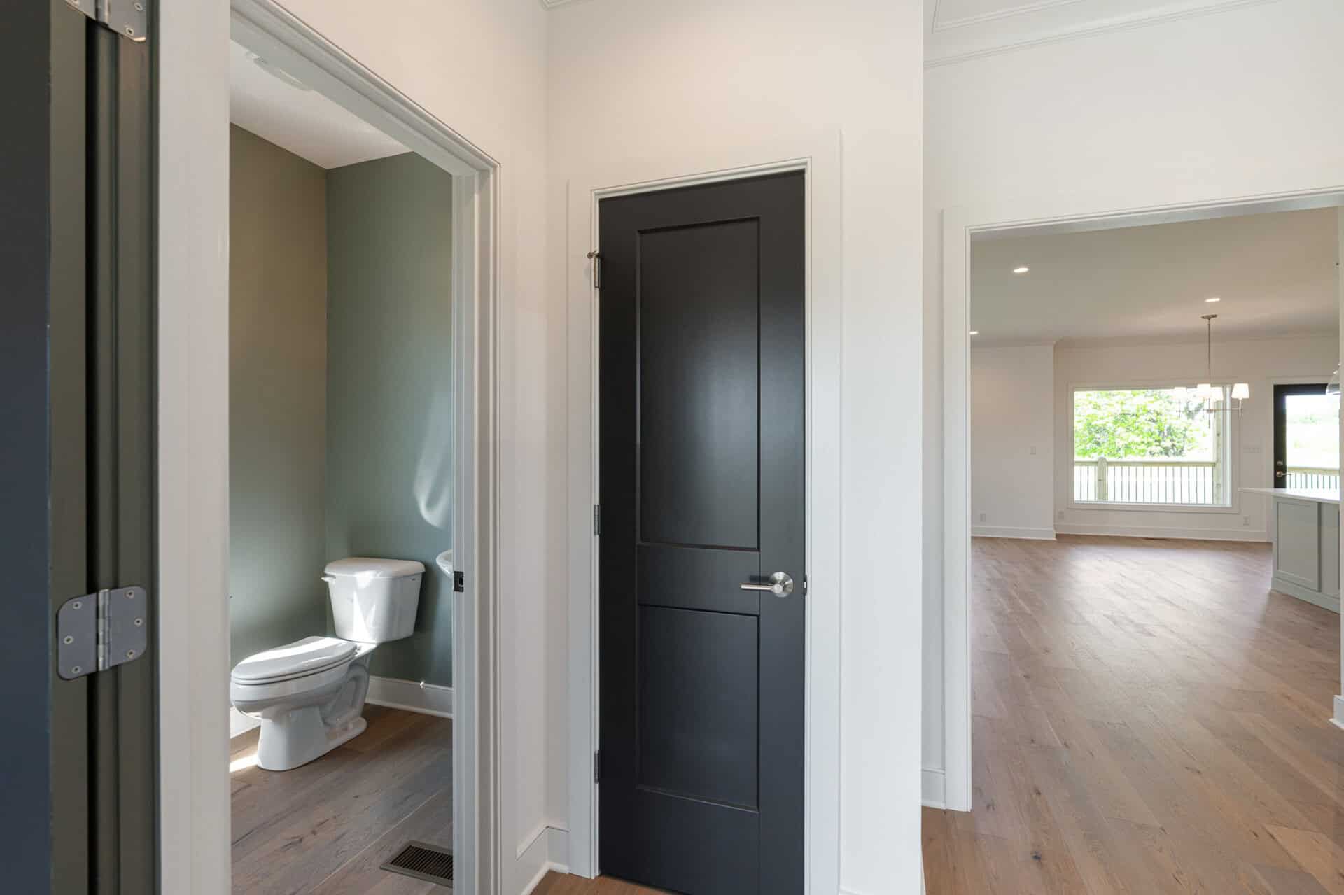 Interior view of a modern home with a bathroom, black door, and spacious living area.