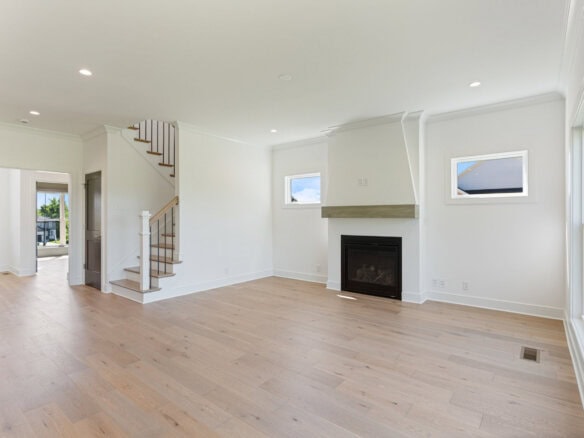 Spacious living room with fireplace, large windows, and light wood flooring.