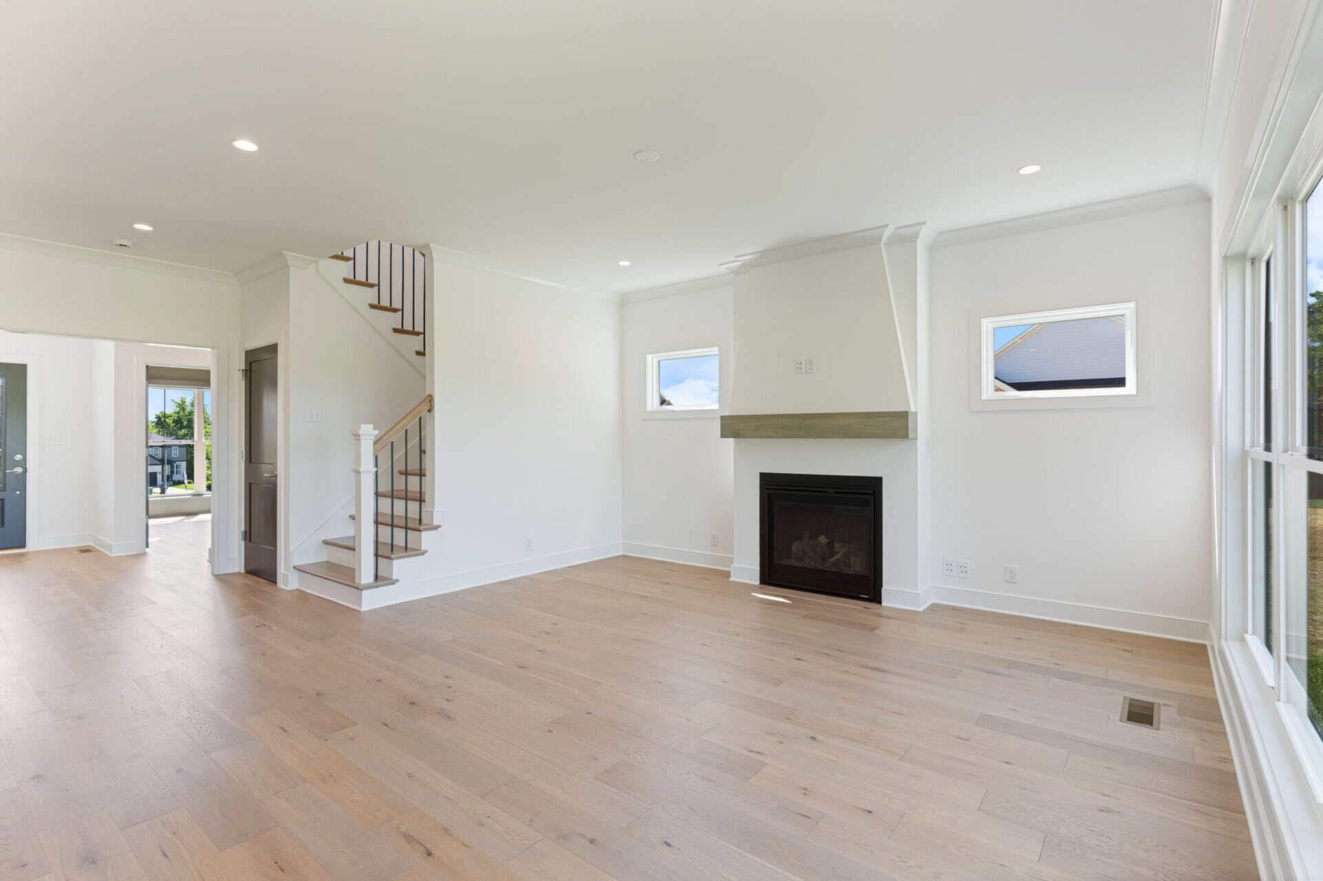 Spacious living room with fireplace, large windows, and light wood flooring.