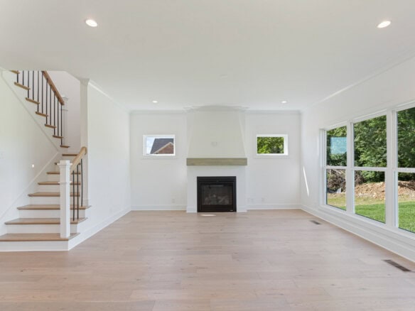 Spacious living room with large windows and modern fireplace in a new home.