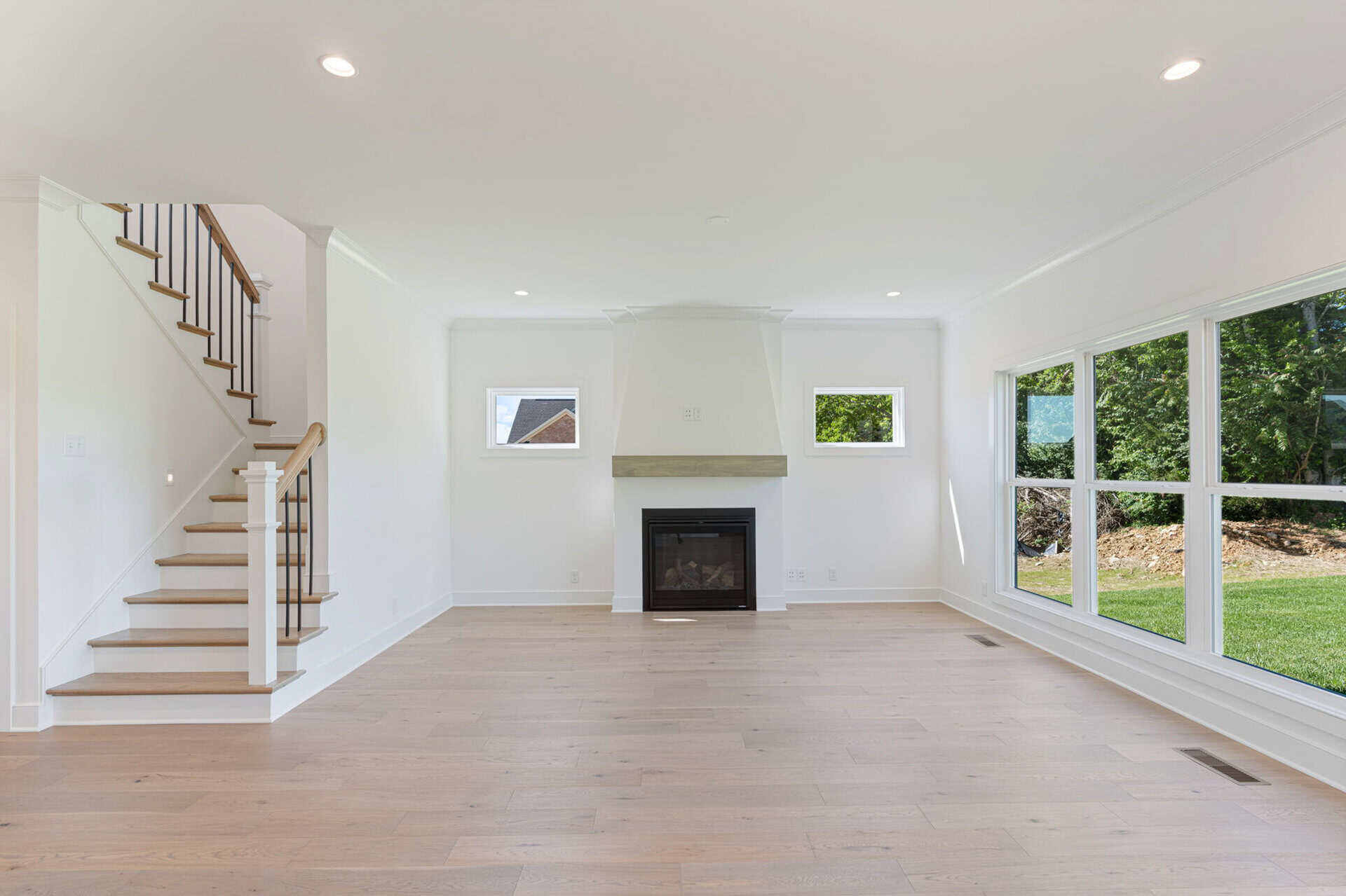Spacious living room with large windows and modern fireplace in a new home.