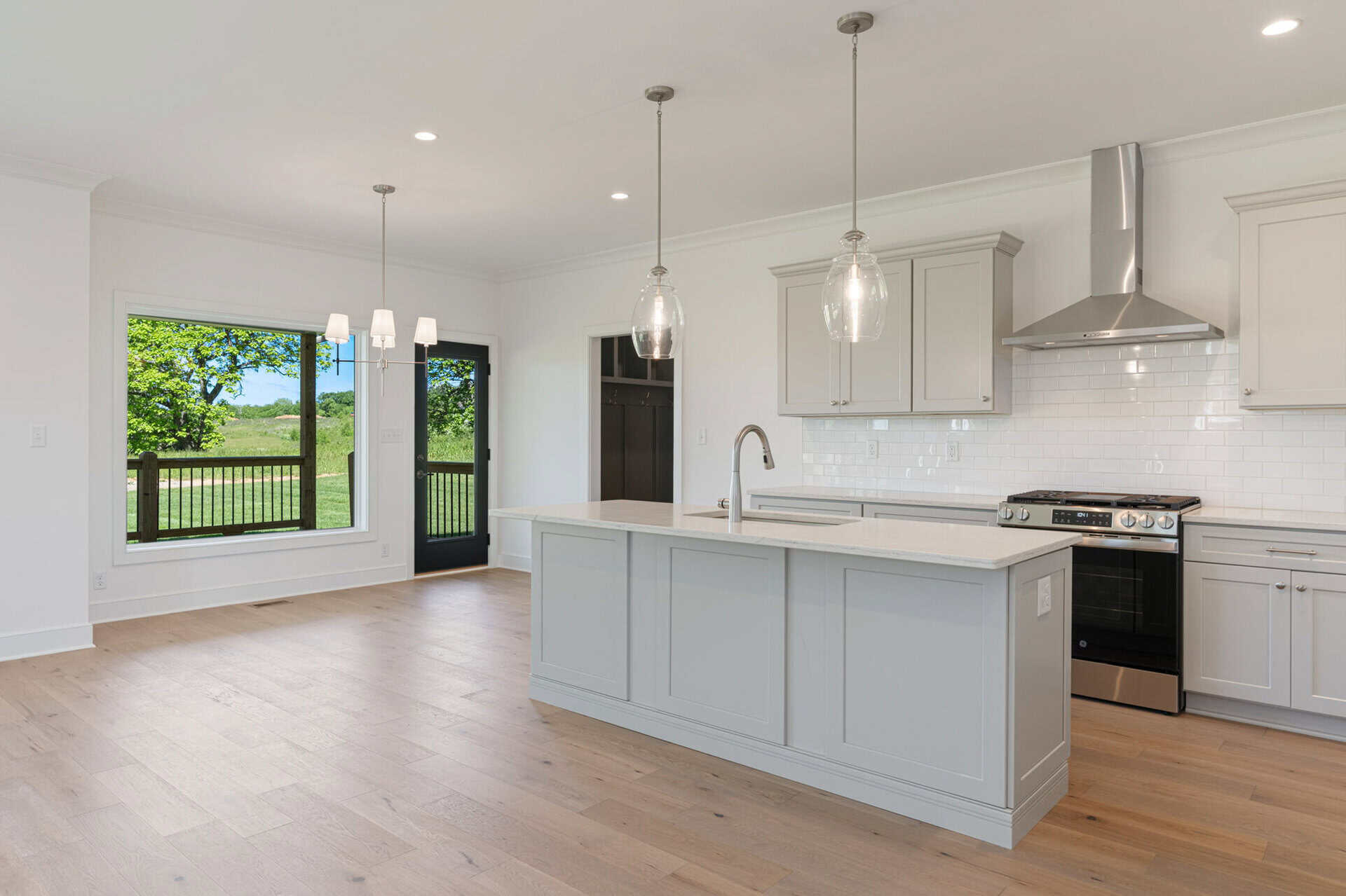Modern kitchen with white cabinets, island, and stainless steel appliances.