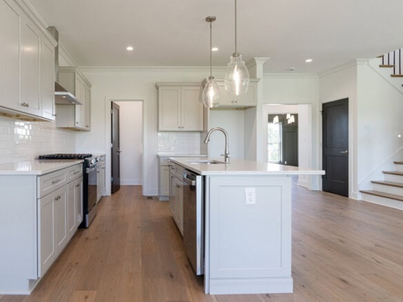 Modern kitchen with white cabinets, island, and pendant lighting in a new home.