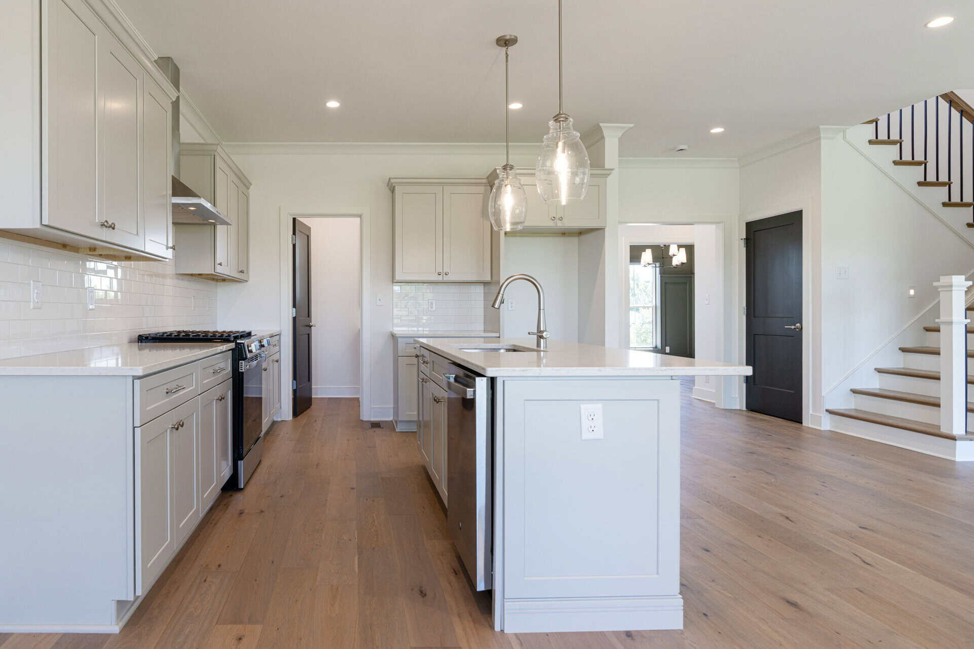 Modern kitchen with white cabinets, island, and pendant lighting in a new home.