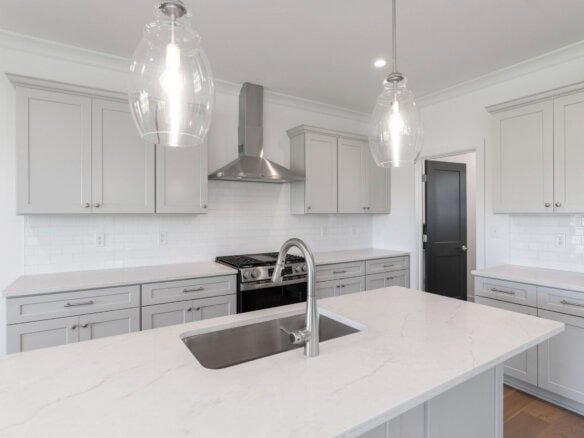 Modern kitchen with white cabinets, marble countertops, and stainless steel appliances.