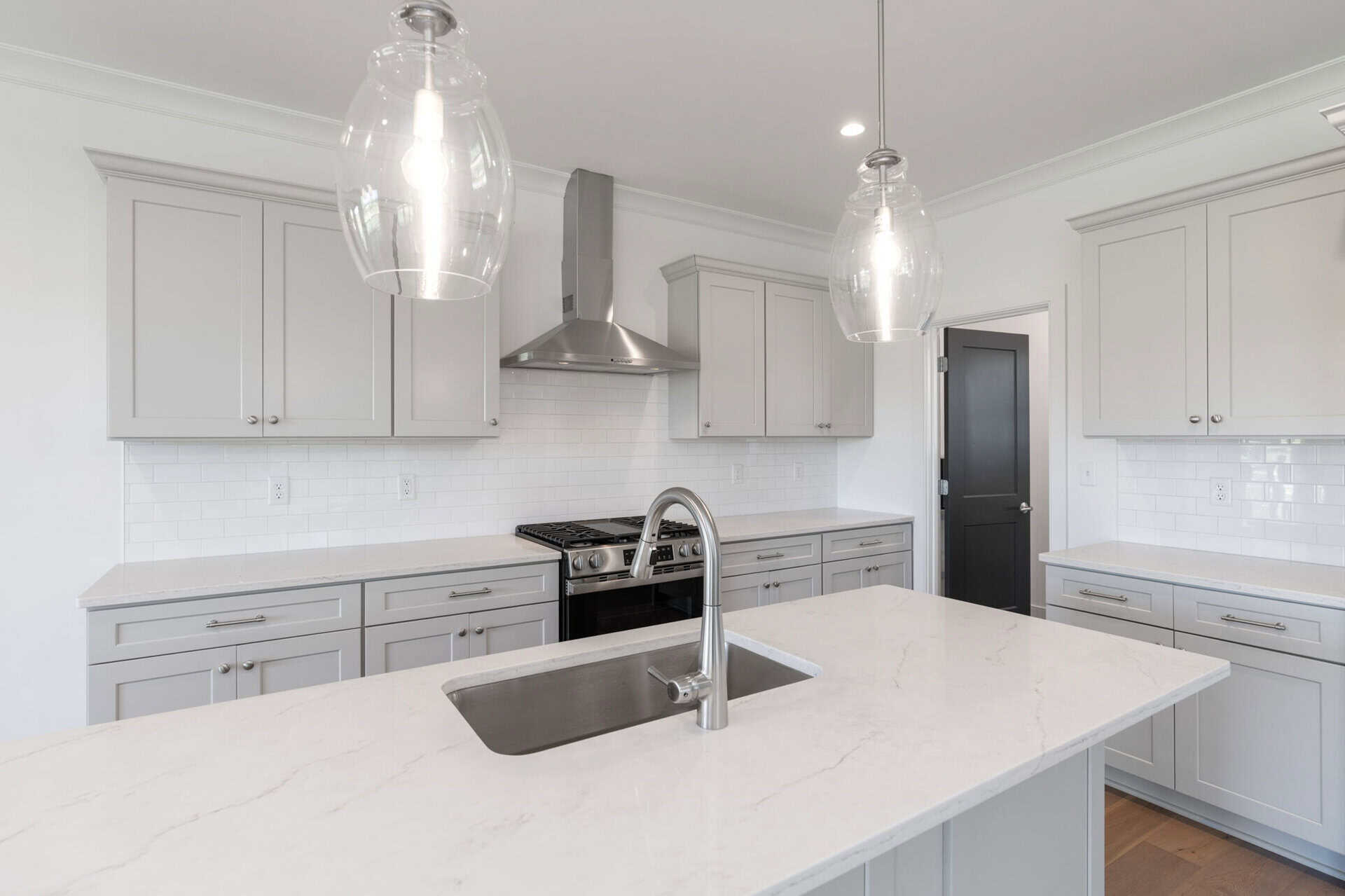Modern kitchen with white cabinets, marble countertops, and stainless steel appliances.