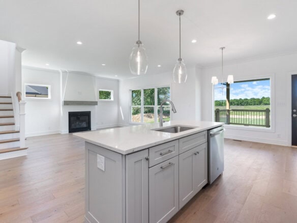 Modern open-concept kitchen with island and large windows overlooking outdoors.