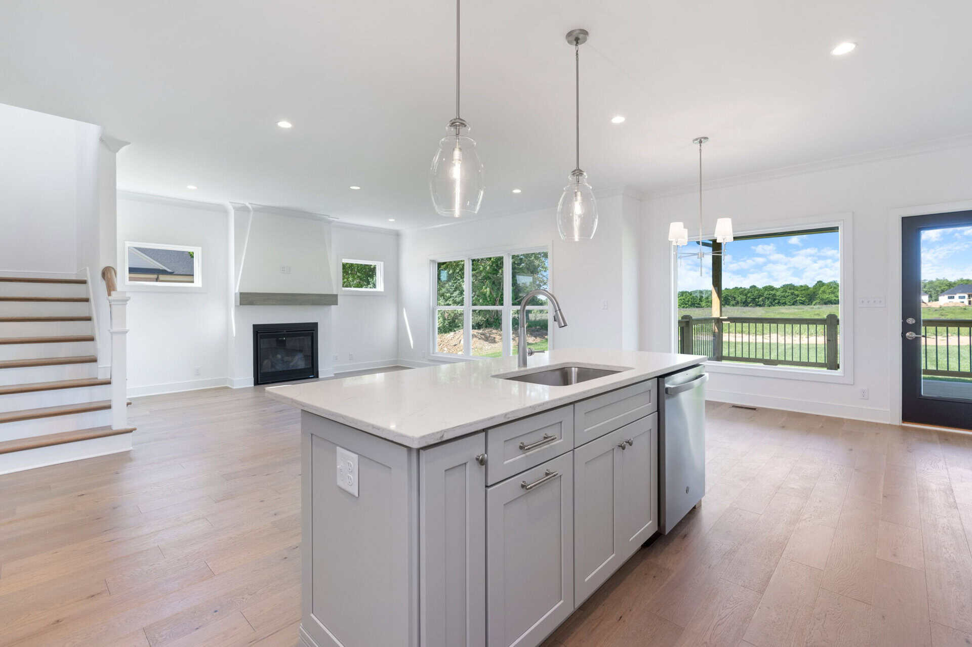 Modern open-concept kitchen with island and large windows overlooking outdoors.