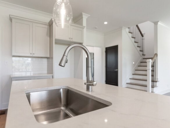 Modern kitchen with white cabinets and stainless steel sink.