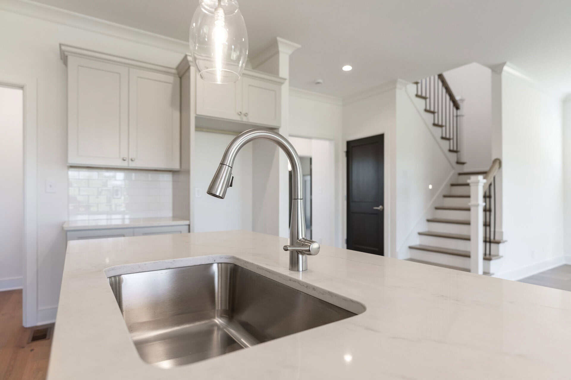 Modern kitchen with white cabinets and stainless steel sink.