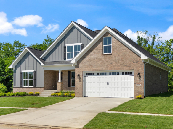Front view of a suburban house with brick and gray siding, two peaked roofs, and a white two-car garage under a blue sky.