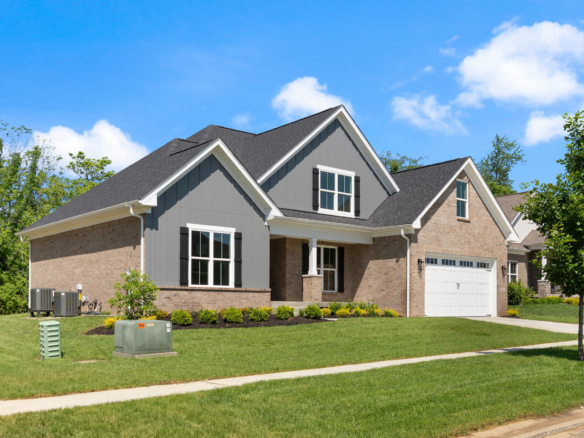 Front view of a two-story brick house with gray siding, white trim, and a double garage under a blue sky.