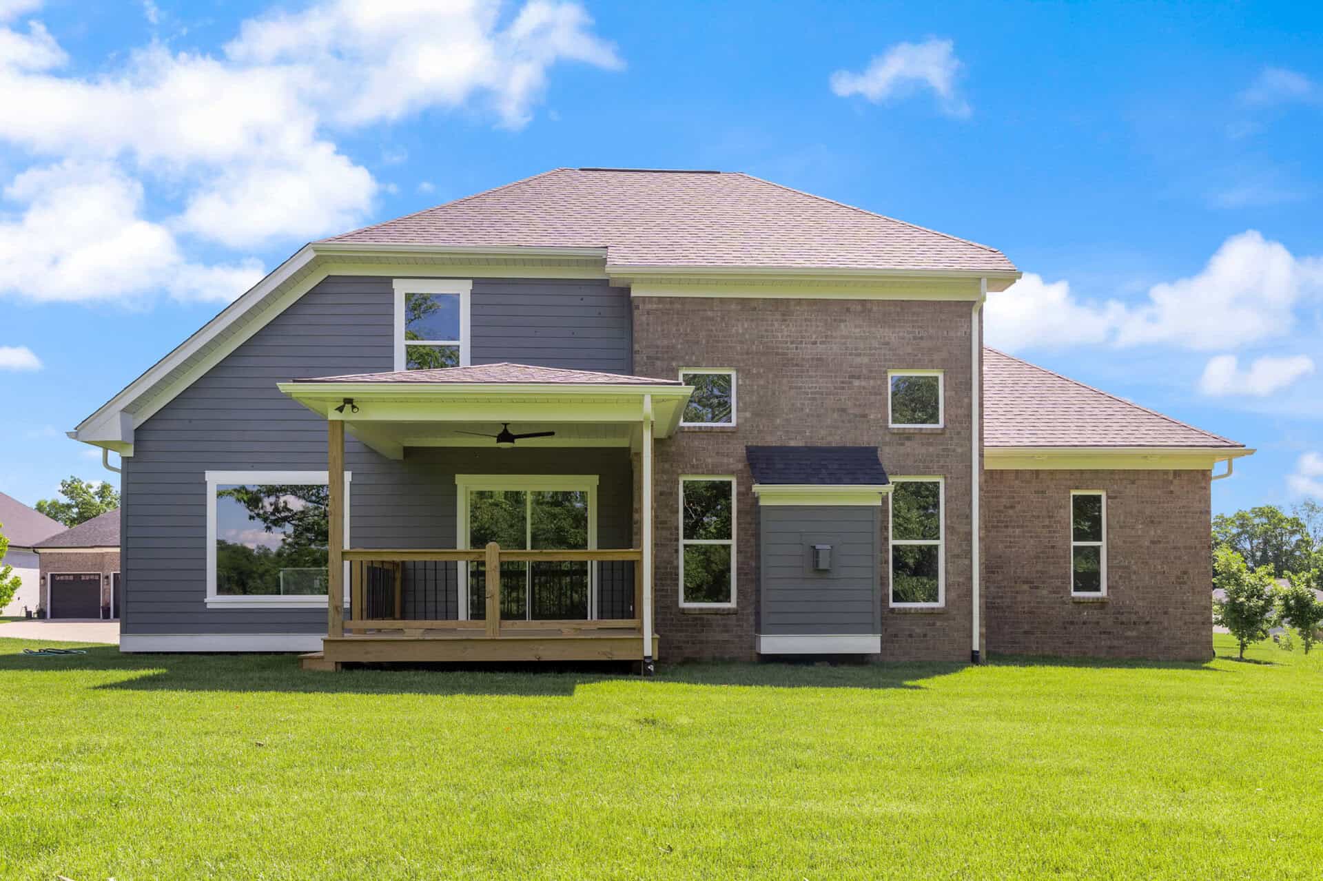 Modern two-story house with a spacious backyard and a covered porch.