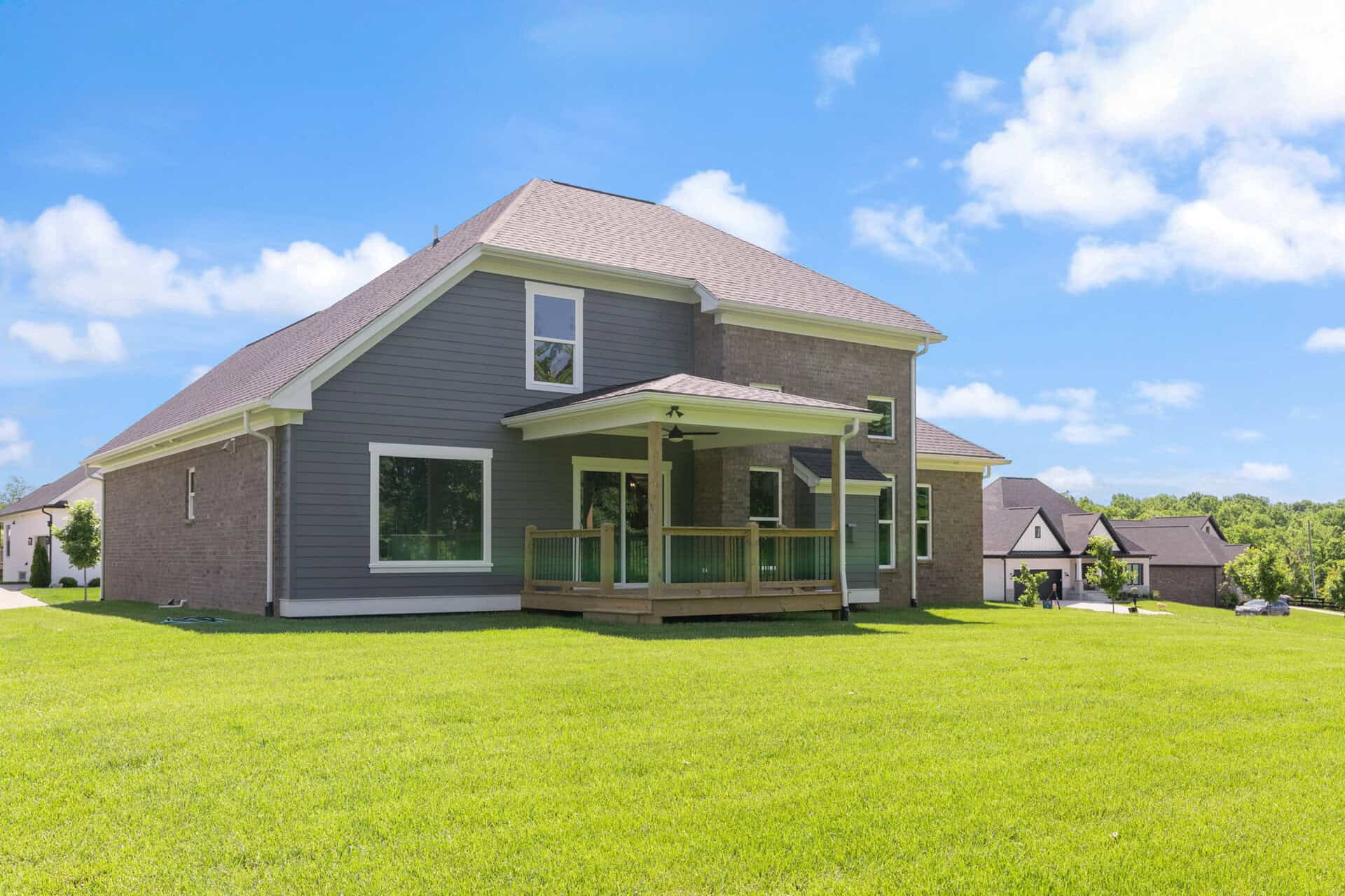 Modern two-story house with a large backyard and a wooden deck in Louisville, KY.