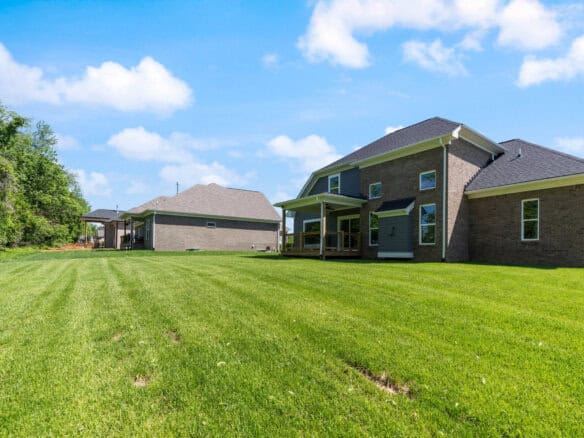 Modern brick home with spacious green lawn and blue sky.