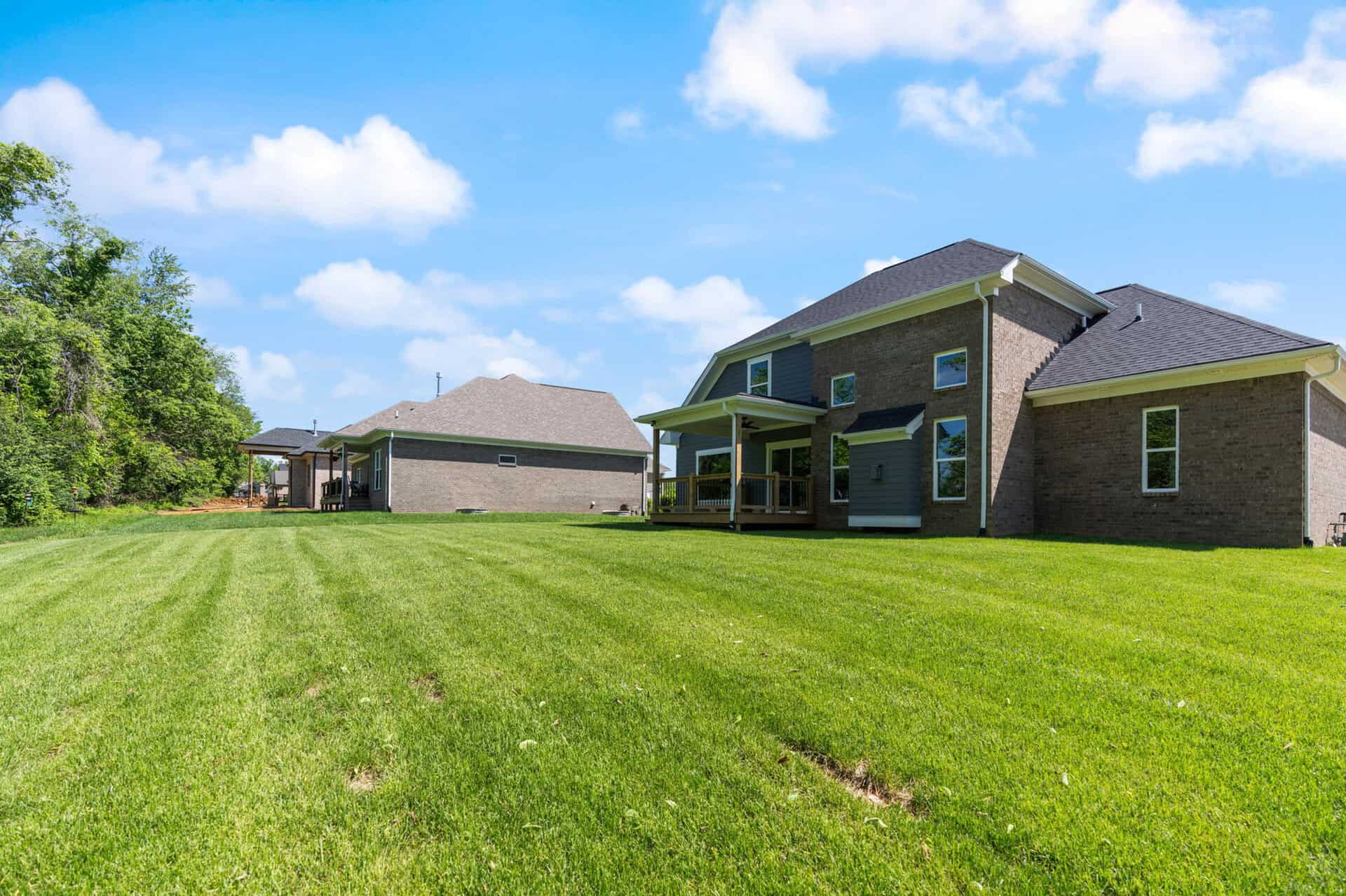Modern brick home with spacious green lawn and blue sky.
