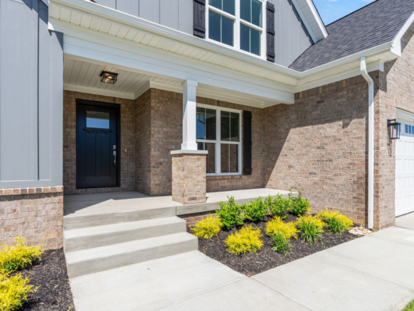 Modern house exterior with brick and siding, front steps, and landscaped yard.