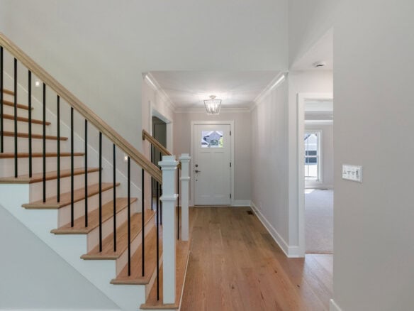 Bright entryway with hardwood floors and staircase in a modern home.