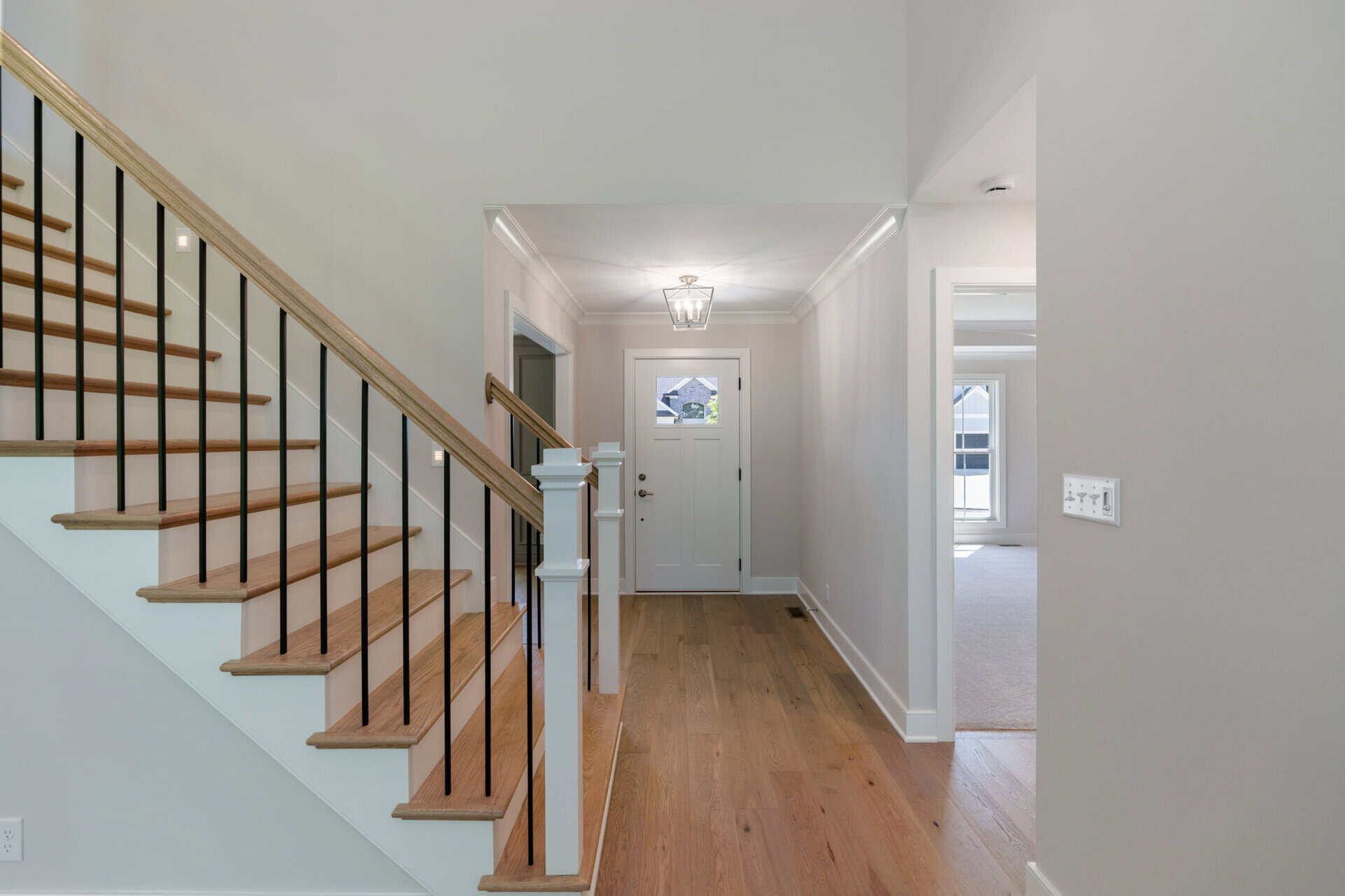 Bright entryway with hardwood floors and staircase in a modern home.