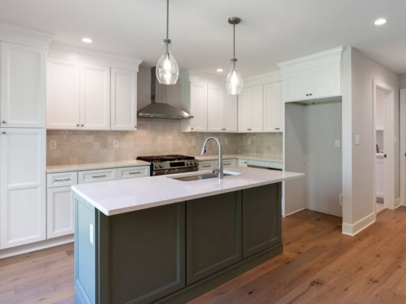 Modern kitchen with white cabinets, island, and pendant lighting in a new home.
