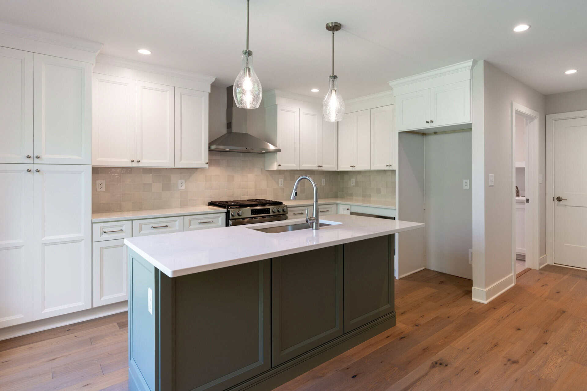 Modern kitchen with white cabinets, island, and pendant lighting in a new home.