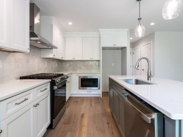 Modern kitchen with white cabinets, stainless steel appliances, and a large island.