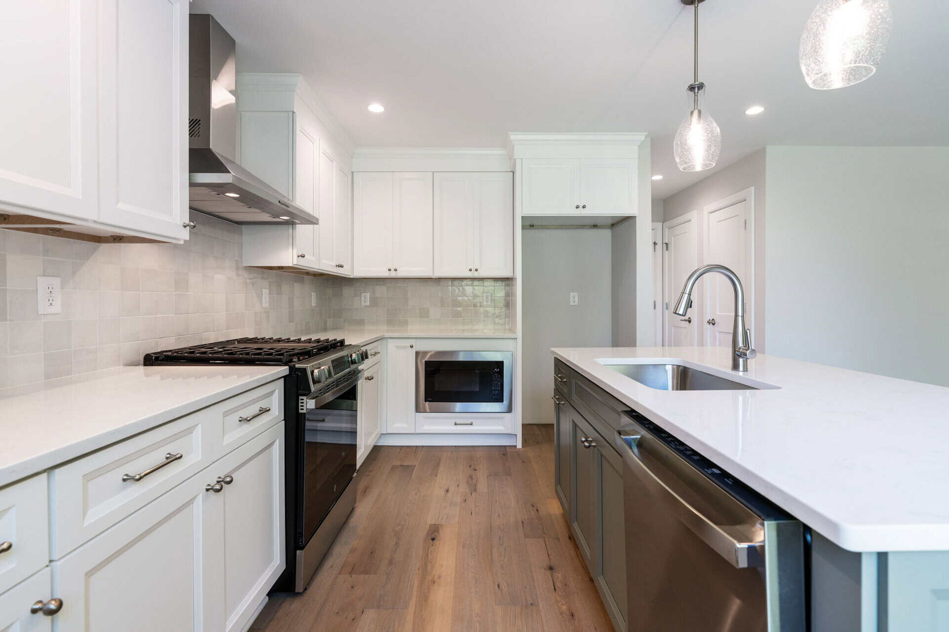 Modern kitchen with white cabinets, stainless steel appliances, and a large island.