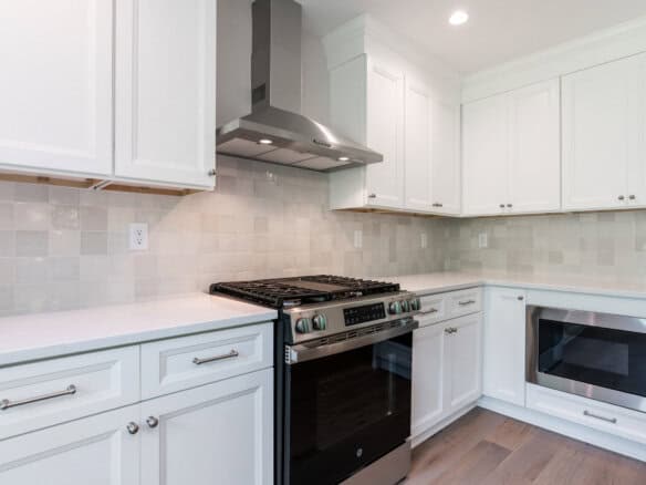 Modern kitchen with white cabinets, stainless steel stove, and microwave.