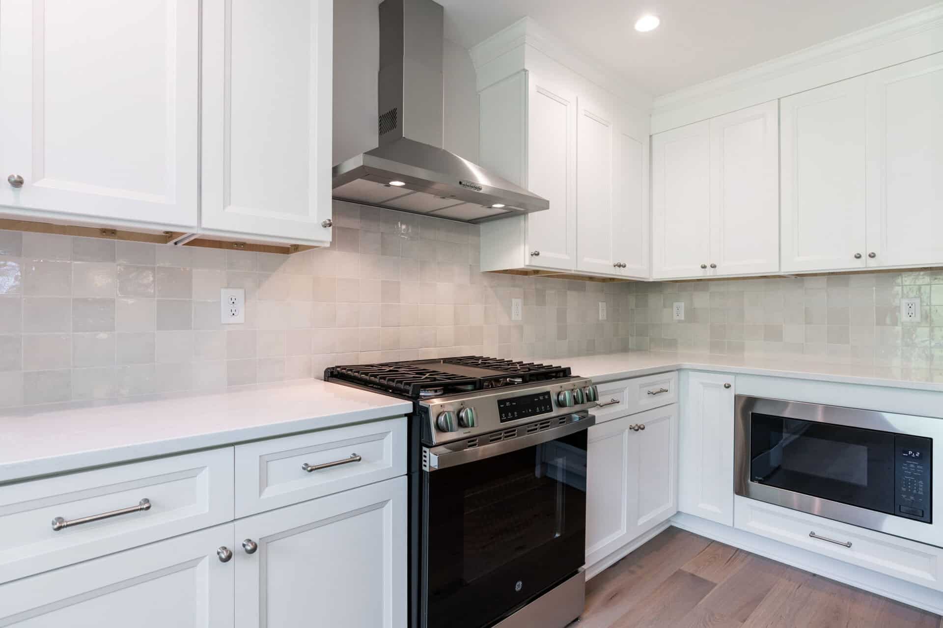 Modern kitchen with white cabinets, stainless steel stove, and microwave.