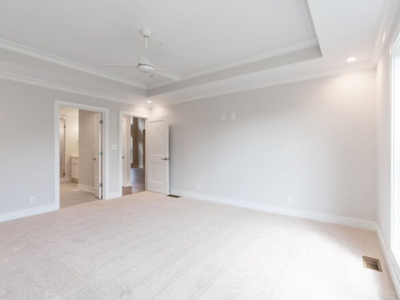 Spacious, bright living room with large window and neutral decor in a custom home.