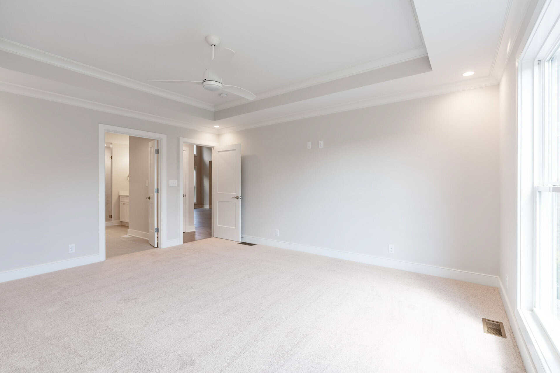 Spacious, bright living room with large window and neutral decor in a custom home.