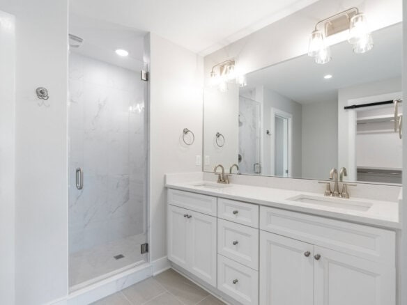 Modern bathroom with double vanity and walk-in shower in a new home.