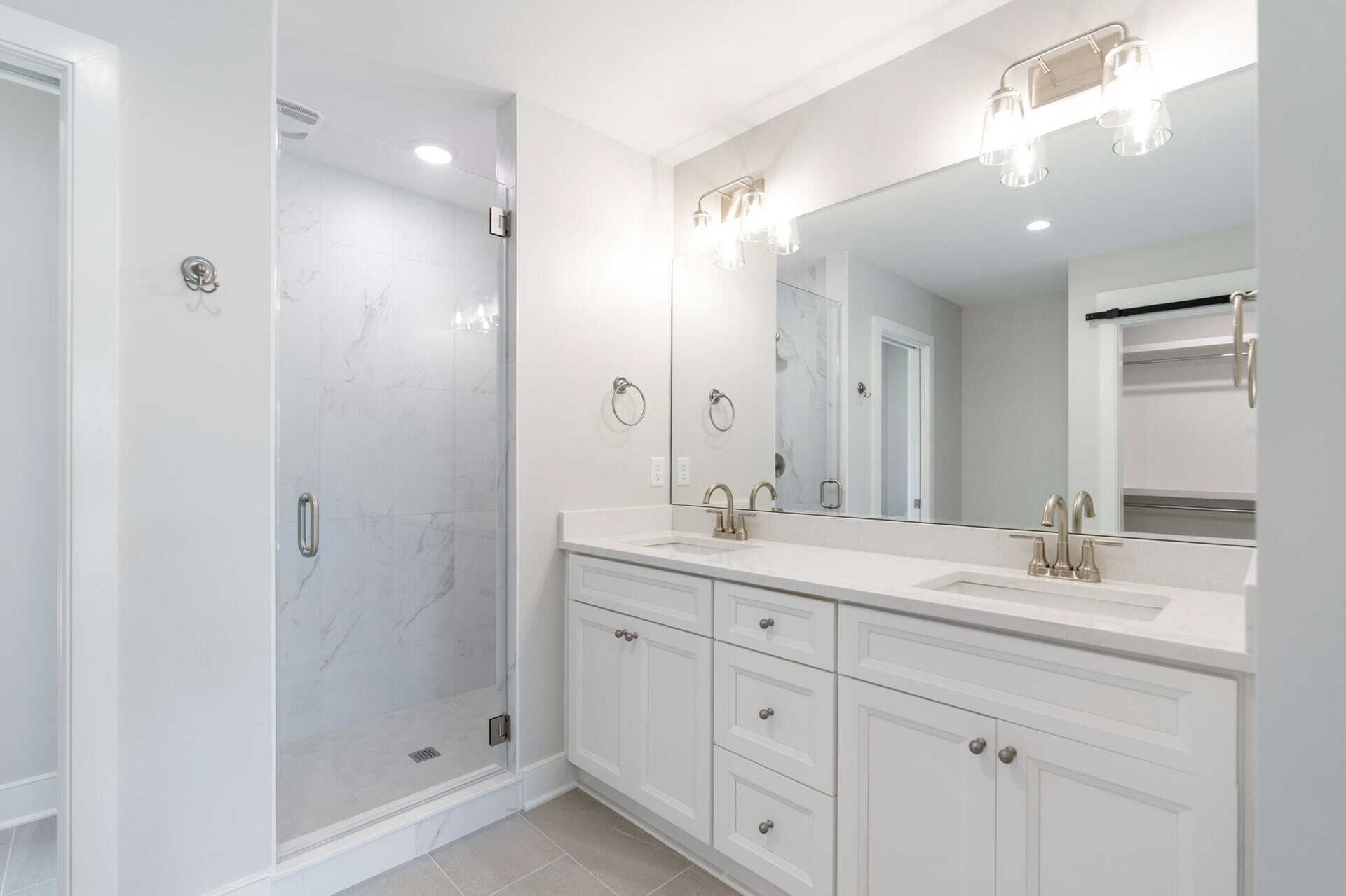 Modern bathroom with double vanity and walk-in shower in a new home.