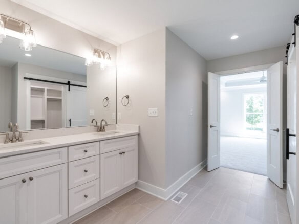 Modern bathroom with double vanity and bright adjacent room.