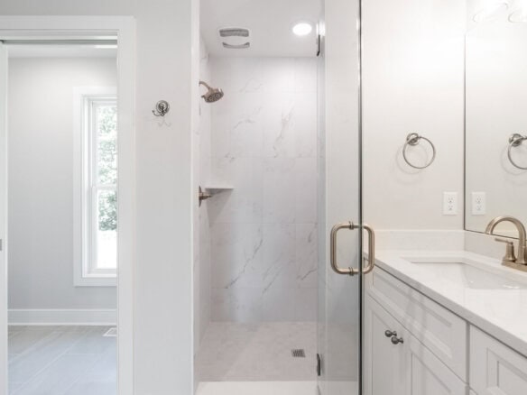Modern bathroom with walk-in shower, white walls, and double vanity.
