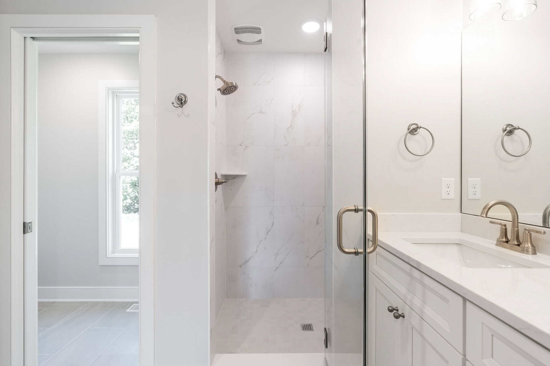 Modern bathroom with walk-in shower, white walls, and double vanity.