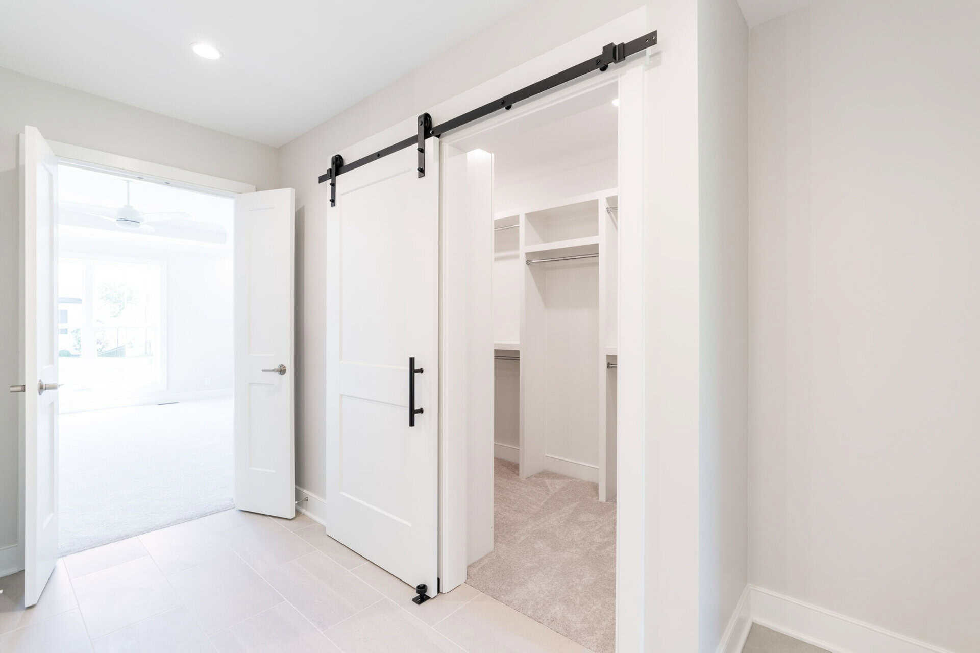 Spacious walk-in closet with white shelves and sliding barn door in modern home.
