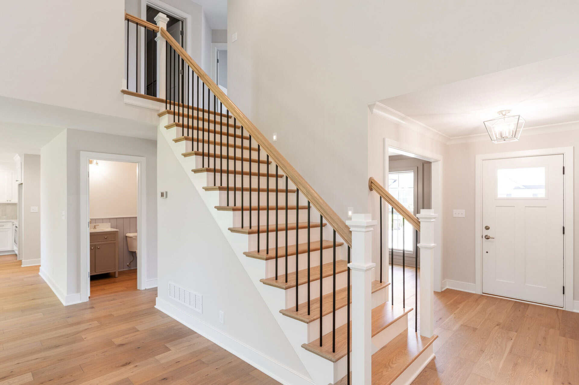 Bright foyer with staircase and hardwood floors in a modern home.