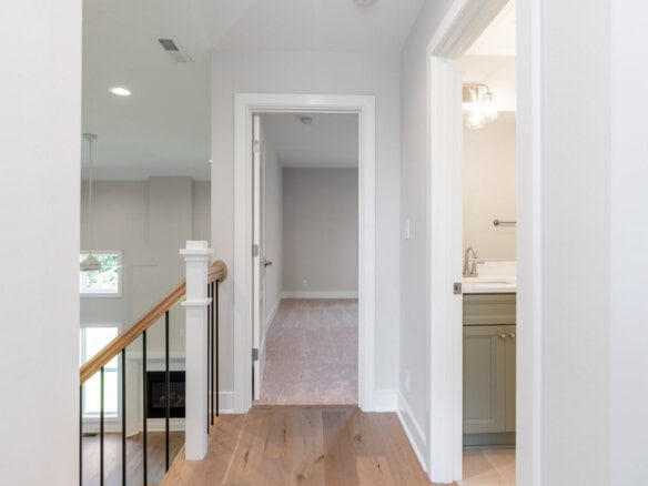 Interior view of a hallway leading to a bedroom and bathroom in a modern home.