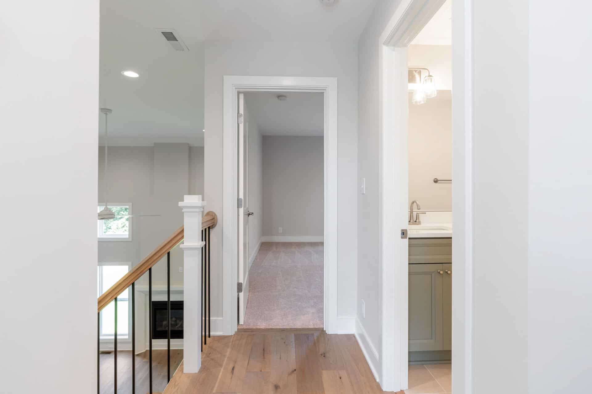 Interior view of a hallway leading to a bedroom and bathroom in a modern home.