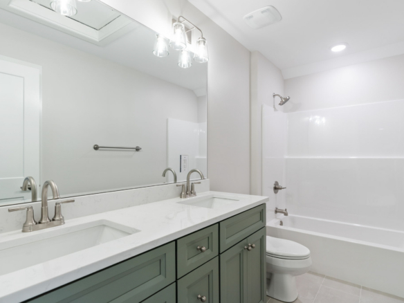 Double-sink bathroom vanity with marble countertop and gray cabinets, large wall mirror, and brushed-nickel fixtures in a bright, modern bathroom.